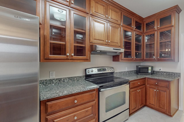 kitchen featuring light tile patterned floors, stainless steel appliances, and dark stone counters