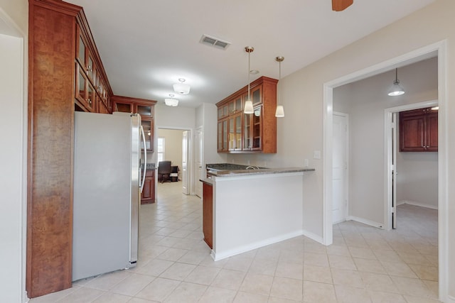 kitchen with kitchen peninsula, stainless steel fridge, light tile patterned floors, and decorative light fixtures