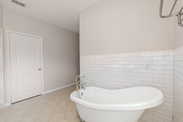 bathroom featuring tile patterned floors, a tub to relax in, and tile walls