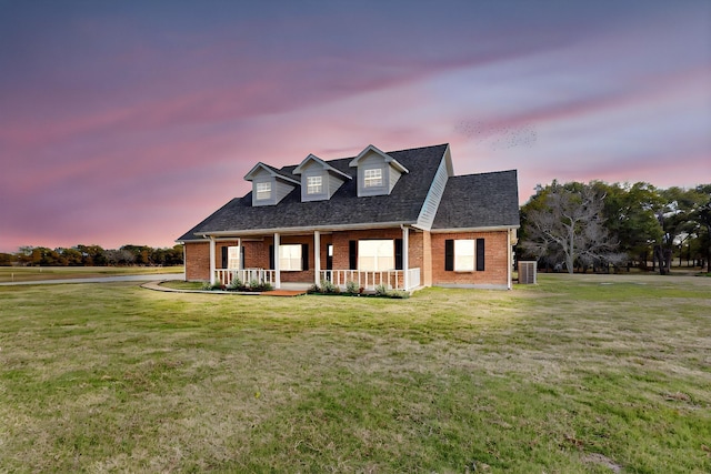 cape cod house featuring a yard, central AC, and a porch