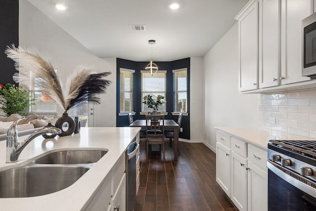 kitchen featuring pendant lighting, backsplash, dark wood-type flooring, white cabinets, and sink