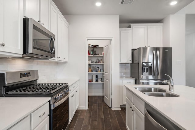 kitchen with decorative backsplash, dark hardwood / wood-style flooring, stainless steel appliances, sink, and white cabinets