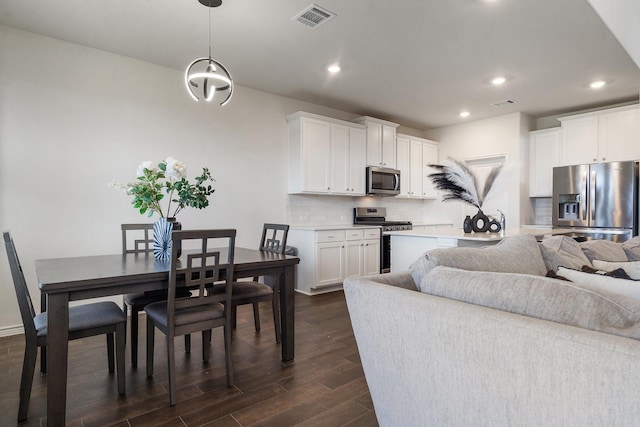 kitchen featuring pendant lighting, white cabinets, decorative backsplash, dark hardwood / wood-style flooring, and stainless steel appliances