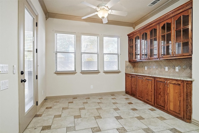 kitchen featuring light stone countertops, backsplash, ceiling fan, and ornamental molding