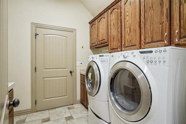 clothes washing area with cabinets and separate washer and dryer