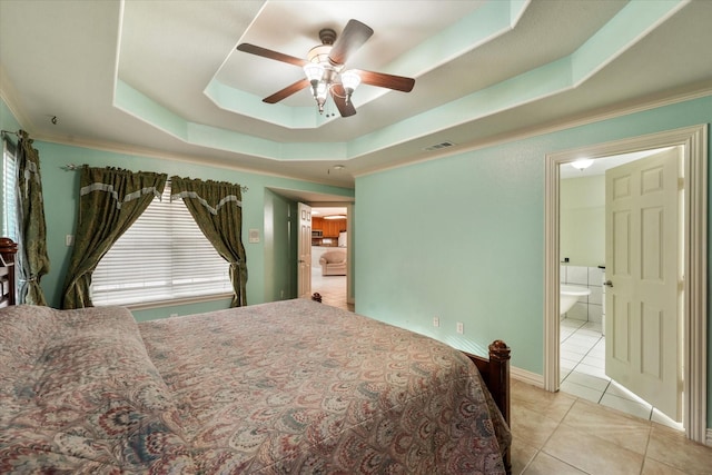 bedroom with ceiling fan, light tile patterned flooring, a raised ceiling, and connected bathroom