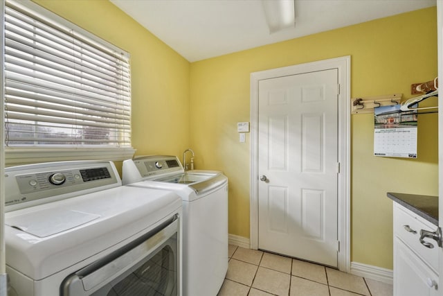 clothes washing area featuring cabinets, light tile patterned flooring, and washing machine and clothes dryer