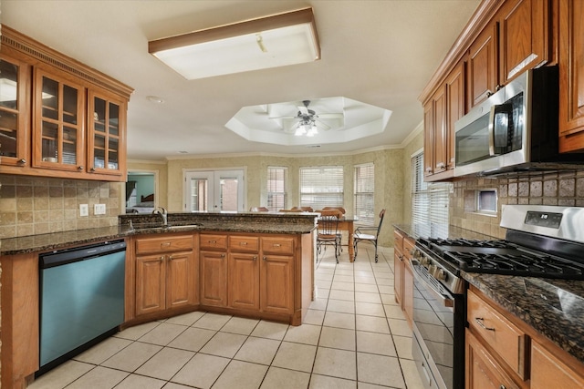 kitchen featuring sink, ceiling fan, dark stone countertops, kitchen peninsula, and stainless steel appliances