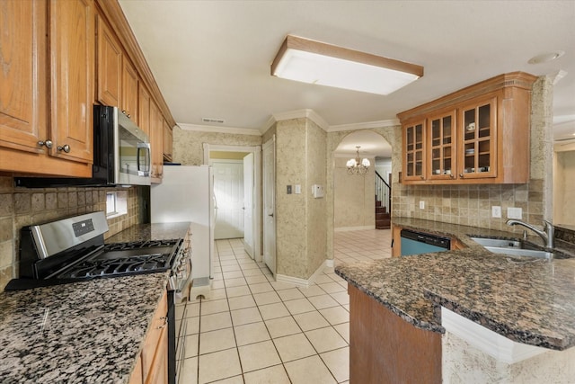 kitchen with sink, light tile patterned floors, crown molding, appliances with stainless steel finishes, and dark stone countertops