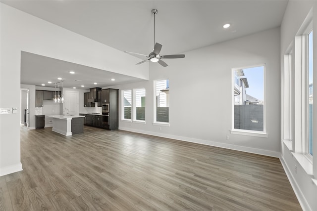 unfurnished living room featuring ceiling fan, wood-type flooring, and sink