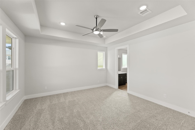 carpeted empty room featuring a raised ceiling and ceiling fan