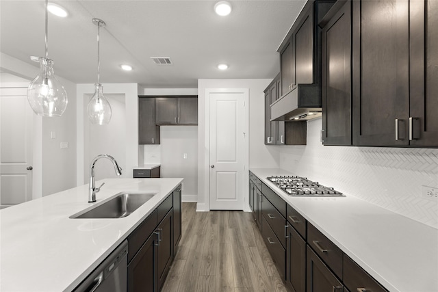 kitchen featuring dark brown cabinetry, stainless steel appliances, sink, decorative light fixtures, and hardwood / wood-style floors