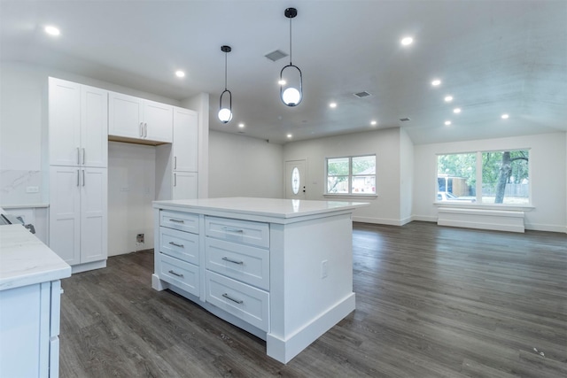 kitchen with light stone countertops, dark wood-type flooring, white cabinets, a center island, and hanging light fixtures