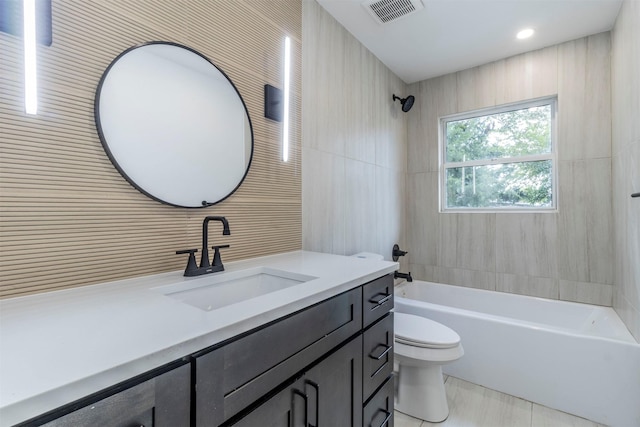 full bathroom with vanity, toilet, tile walls, and tiled shower / bath combo