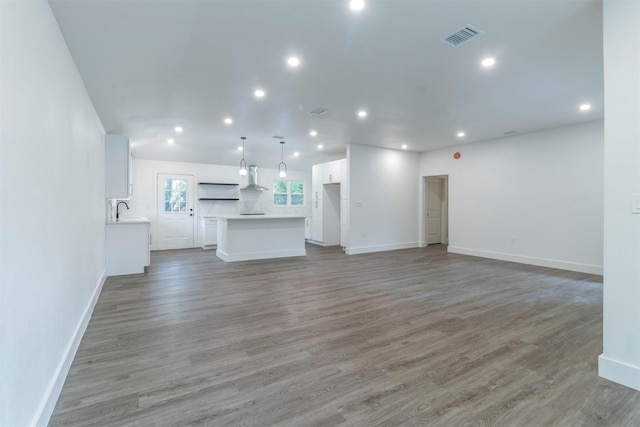 unfurnished living room featuring hardwood / wood-style flooring and sink