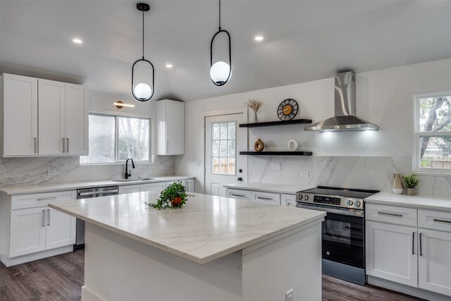 kitchen featuring white cabinets, appliances with stainless steel finishes, a kitchen island, and wall chimney exhaust hood