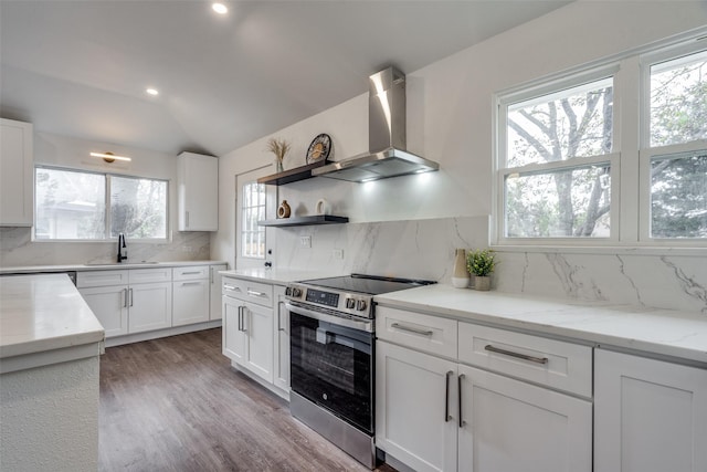 kitchen featuring tasteful backsplash, wall chimney exhaust hood, vaulted ceiling, electric range, and white cabinetry