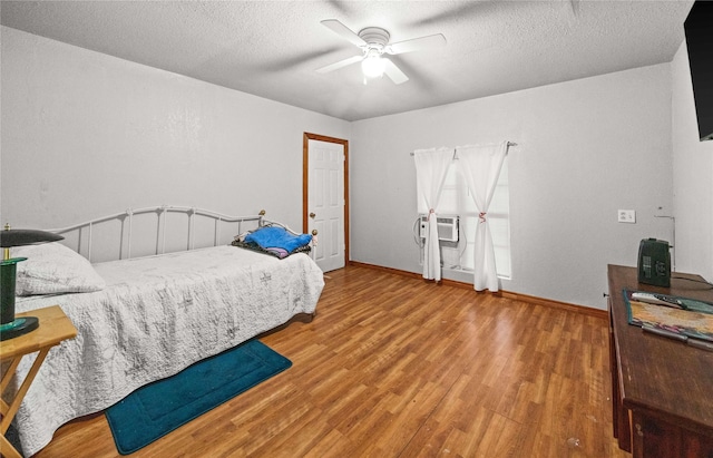 bedroom with ceiling fan, hardwood / wood-style floors, and a textured ceiling