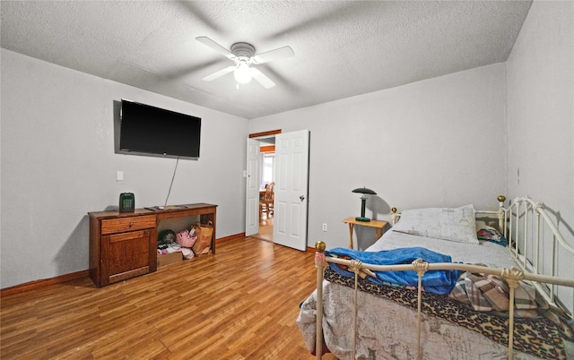 bedroom with a textured ceiling, wood finished floors, a ceiling fan, and baseboards