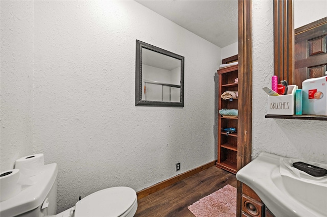 bathroom featuring baseboards, a textured wall, toilet, and wood finished floors