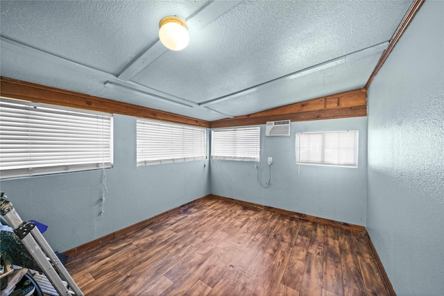 unfurnished room featuring dark wood-type flooring, lofted ceiling, a textured ceiling, and an AC wall unit