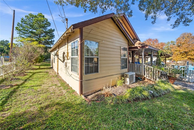 view of property exterior with central AC and a lawn