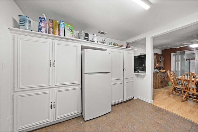 kitchen featuring white fridge, white cabinets, and ceiling fan