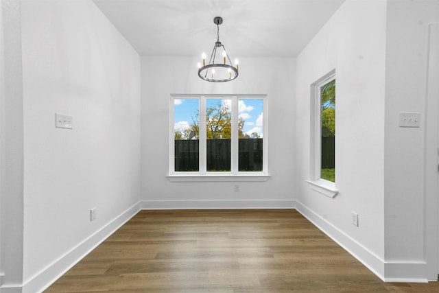 unfurnished dining area featuring a notable chandelier and wood-type flooring