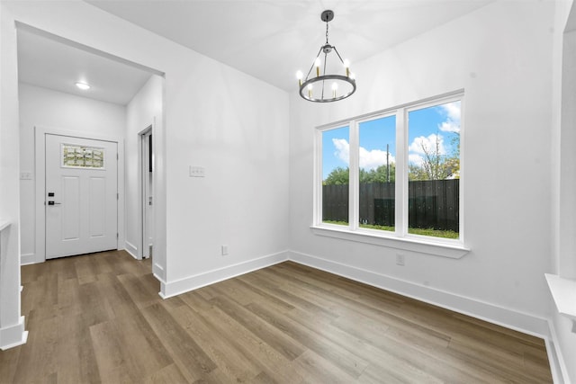 unfurnished dining area featuring light hardwood / wood-style flooring and a chandelier