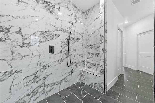 bathroom with tile patterned flooring and a tile shower