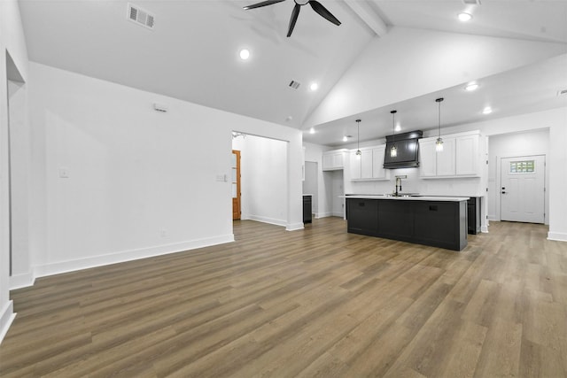 kitchen featuring white cabinets, pendant lighting, an island with sink, and hardwood / wood-style floors