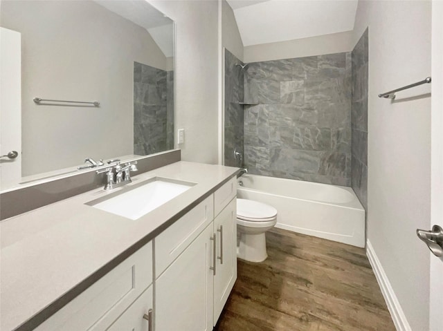 full bathroom with tiled shower / bath, hardwood / wood-style floors, lofted ceiling, vanity, and toilet