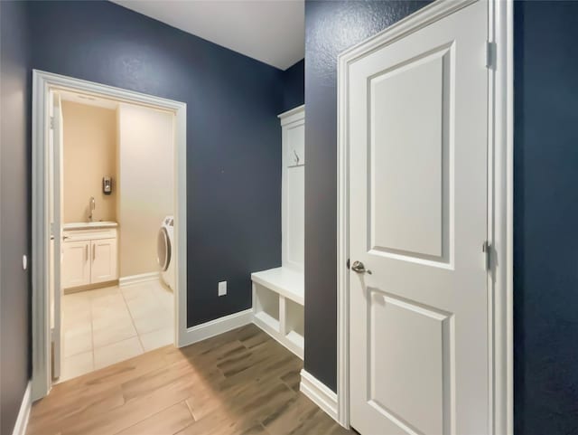 mudroom featuring washer / clothes dryer, sink, and light wood-type flooring