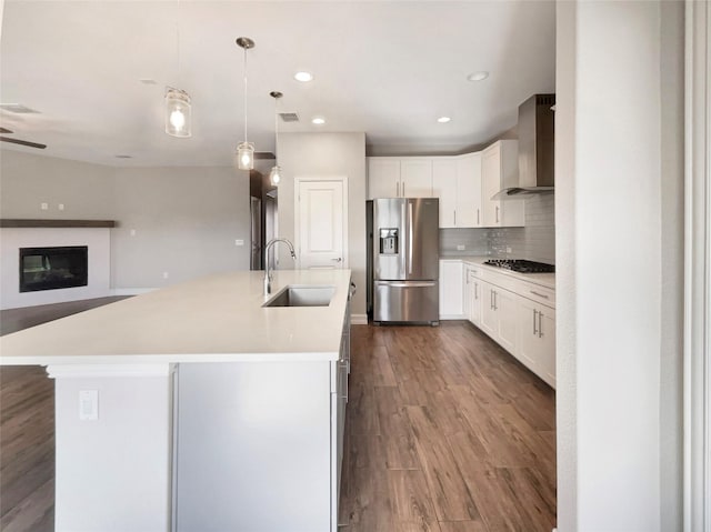 kitchen featuring white cabinets, appliances with stainless steel finishes, sink, and wall chimney range hood