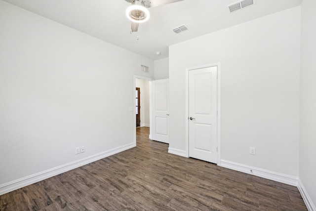 empty room featuring dark wood-type flooring, visible vents, and ceiling fan