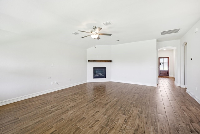 unfurnished living room featuring visible vents, a ceiling fan, and dark wood finished floors