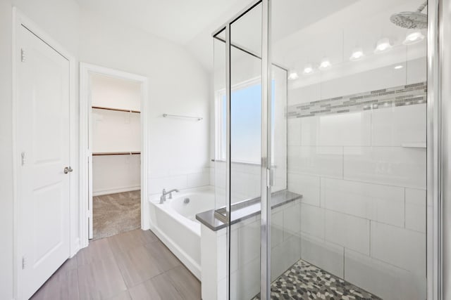 bathroom featuring a shower stall, a garden tub, and vaulted ceiling