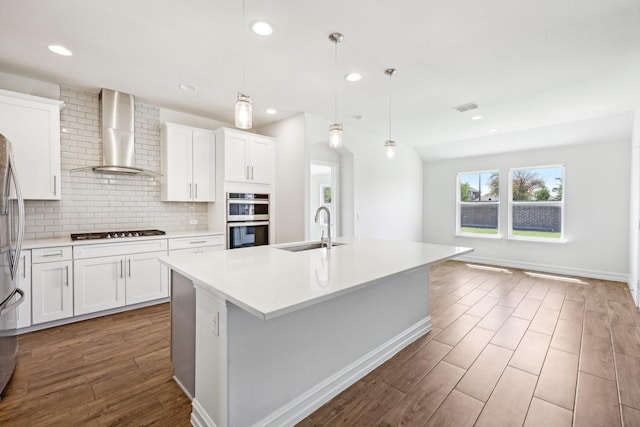 kitchen with a sink, decorative backsplash, appliances with stainless steel finishes, and wall chimney exhaust hood