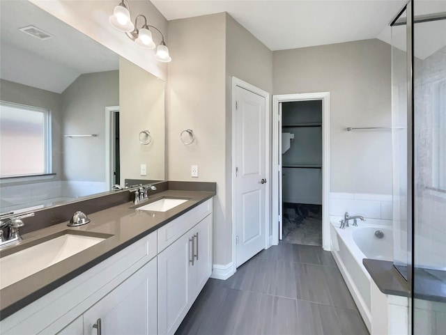 bathroom featuring vanity, tile patterned flooring, vaulted ceiling, and a tub