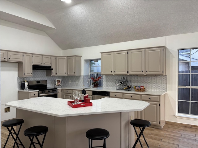 kitchen with a breakfast bar area, tasteful backsplash, light hardwood / wood-style flooring, and appliances with stainless steel finishes