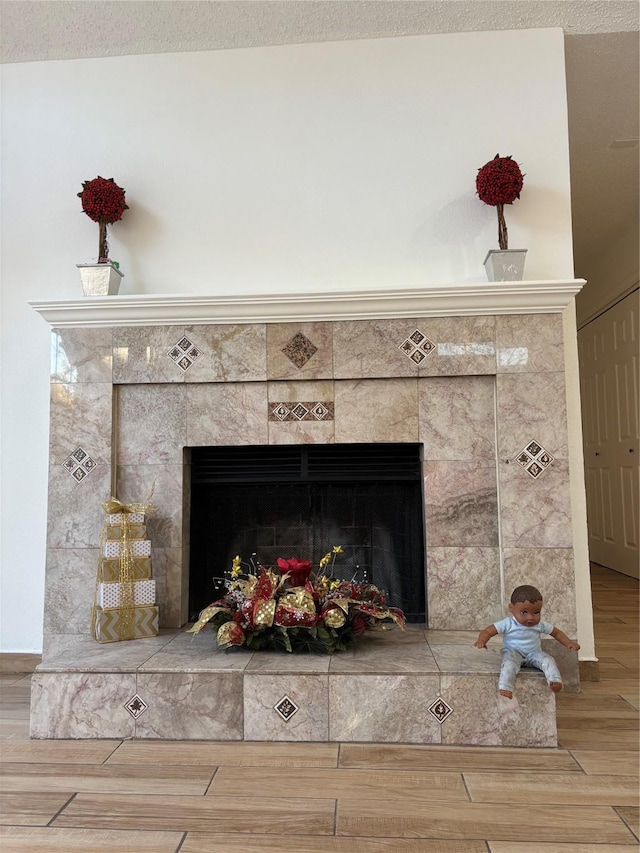 interior details with a tile fireplace, wood-type flooring, and a textured ceiling