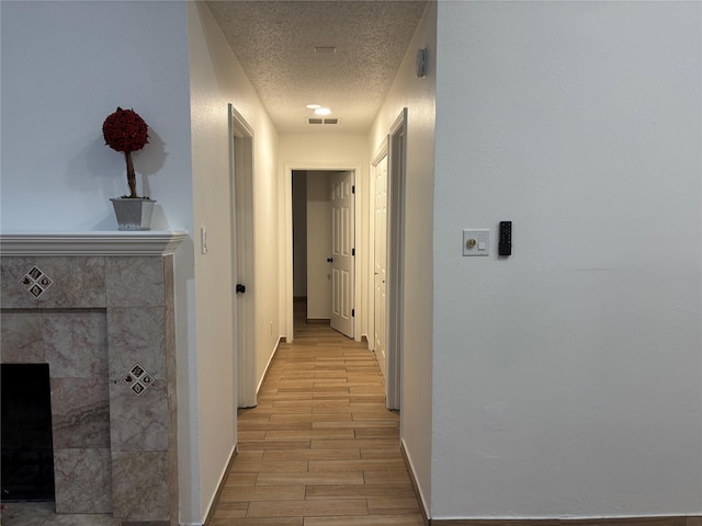 hall featuring a textured ceiling and light hardwood / wood-style flooring