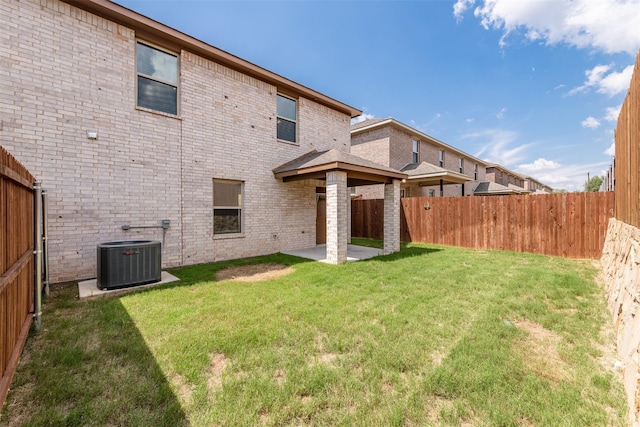 back of house with central air condition unit, a lawn, and a patio