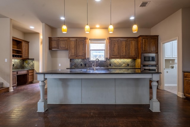 kitchen featuring a center island with sink, decorative light fixtures, sink, and stainless steel appliances