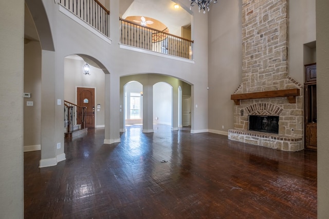 unfurnished living room with a stone fireplace, dark hardwood / wood-style flooring, and a high ceiling