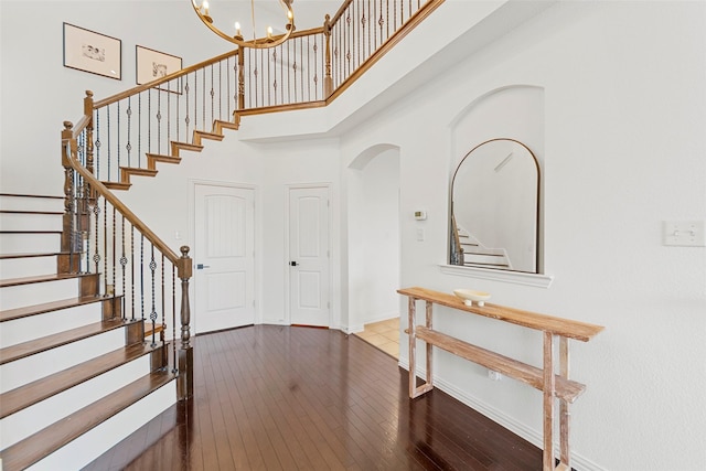 foyer entrance with a towering ceiling, dark hardwood / wood-style floors, and an inviting chandelier