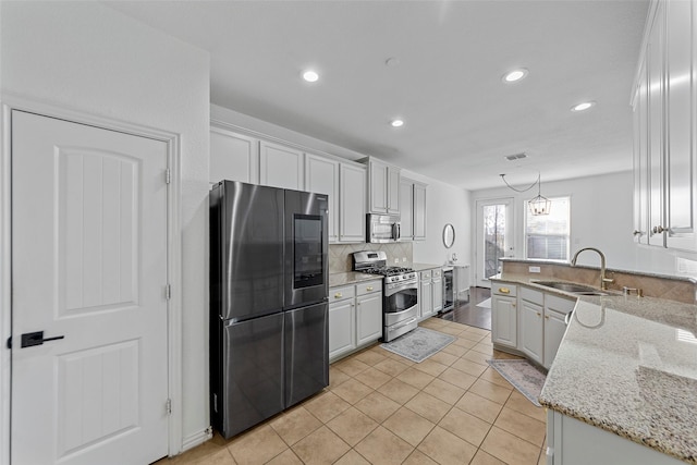 kitchen with white cabinets, sink, light tile patterned flooring, light stone counters, and stainless steel appliances