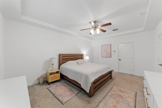 bedroom with light carpet, a raised ceiling, and ceiling fan