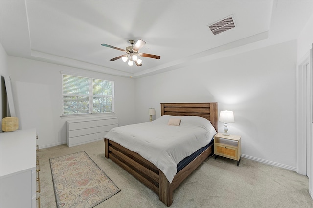 bedroom with a tray ceiling, ceiling fan, and light carpet