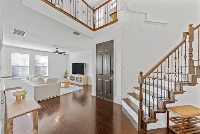 living room featuring a towering ceiling, dark hardwood / wood-style floors, and ceiling fan